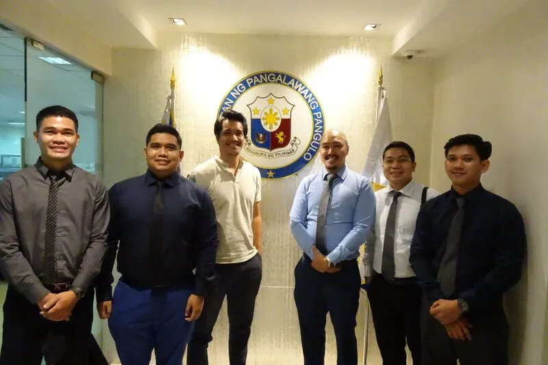 Project team posing in front of the Office of the Vice President seal